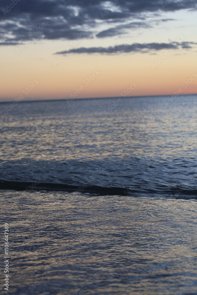 Obraz premium sunset over the ocean evening on sea with small waves yellow sky with dark clouds