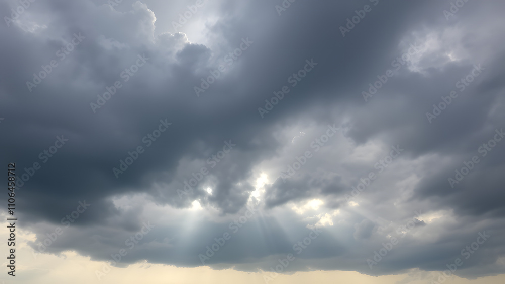 A cloudy sky with dramatic gray clouds against a backdrop of pale blue and faint sunlig A cloudy sky with dramatic gray clouds against a backdrop of pale blue and faint sunlig