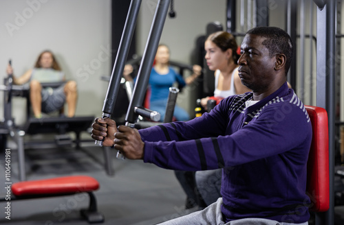 African-american man training on chest fly machine in gym photo