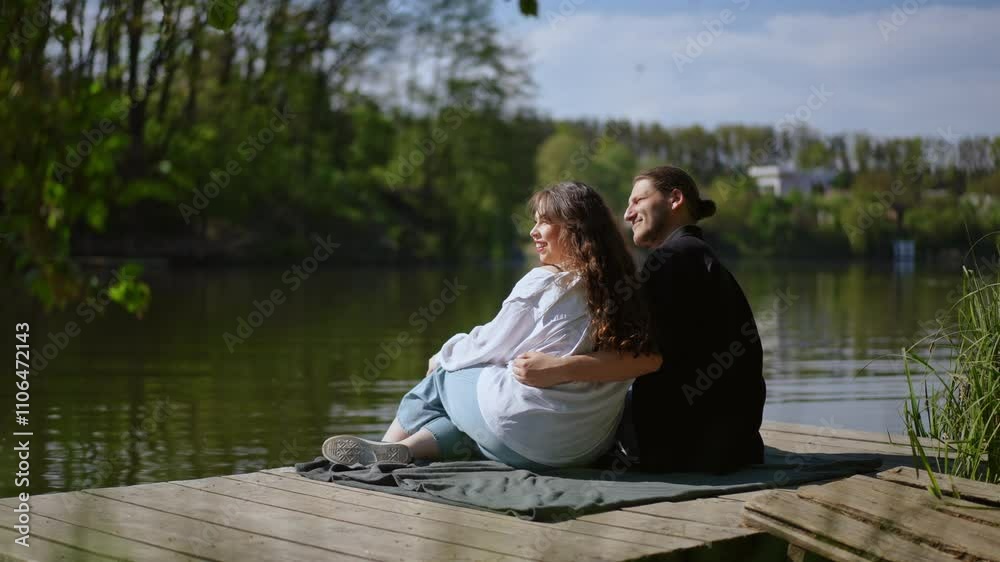 Two individuals relax by the water, enjoying a tranquil moment together and the beauty of nature around them Two individuals relax by the water, enjoying a tranquil moment together and the beauty of nature around them