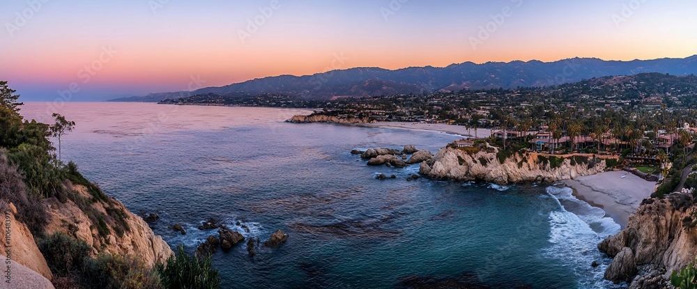 Panoramic sunset view of ocean, beach, cliffs, and coastal town. Panoramic sunset view of ocean, beach, cliffs, and coastal town.