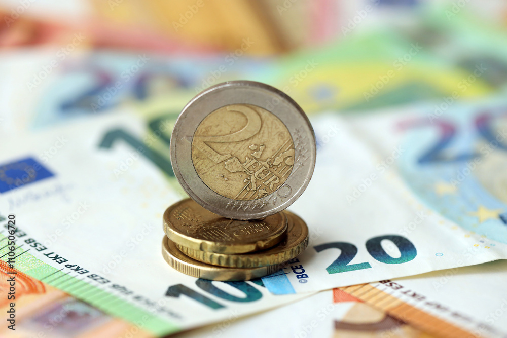 Two euro coin lies on huge amount of different euro dollars banknotes Two euro coin lies on huge amount of different euro dollars banknotes