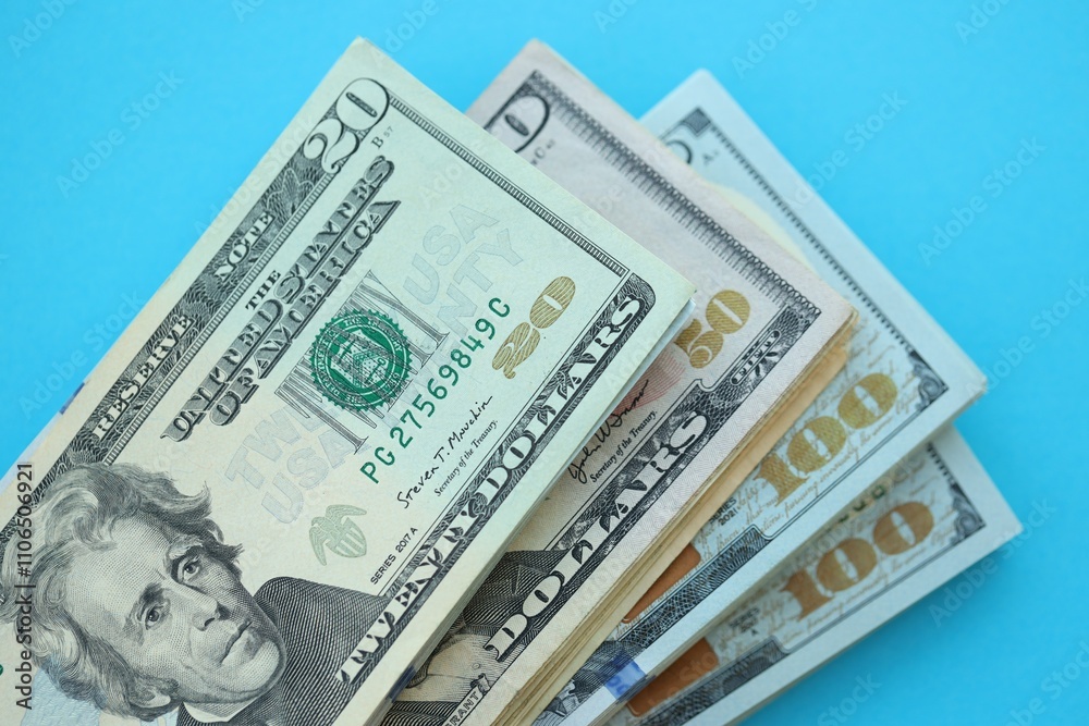 Big amount of hundred, fifty and twenty dollar bills in thick stack lies on bright blue color paper background Big amount of hundred, fifty and twenty dollar bills in thick stack lies on bright blue color paper background