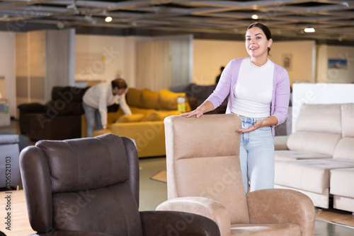 Furniture saleswoman offering armchairs in furniture store photo