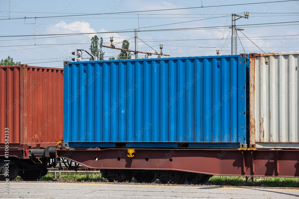 A blue shipping container loaded on a train, illustrating intermodal transport and the logistics industry. A blue shipping container loaded on a train, illustrating intermodal transport and the logistics industry.