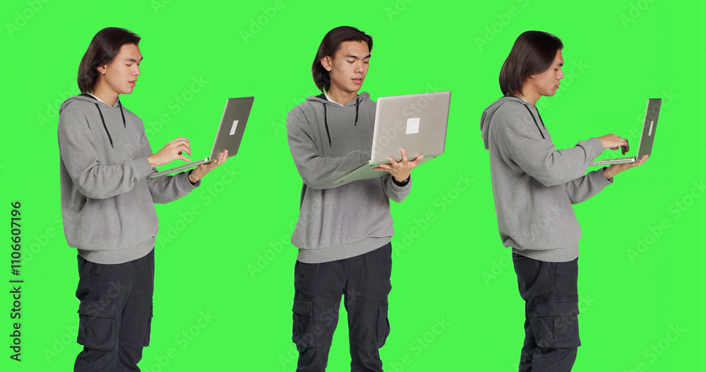 Modern guy navigating web on laptop standing over greenscreen backdrop, browsing online website using wireless computer. Young adult checking social media or working on business. Modern guy navigating web on laptop standing over greenscreen backdrop, browsing online website using wireless computer. Young adult checking social media or working on business.