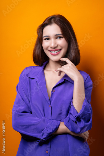 Portrait young cheerful asian woman wearing purple shirt happy smile isolated on yellow background.