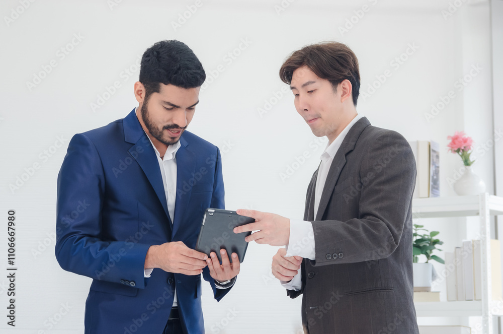 Business man asian two person wearing a black suit handsome standing looking success committed hand holding mobile phone and laptop ready for work marketing in room office, with white background Business man asian two person wearing a black suit handsome standing looking success committed hand holding mobile phone and laptop ready for work marketing in room office, with white background