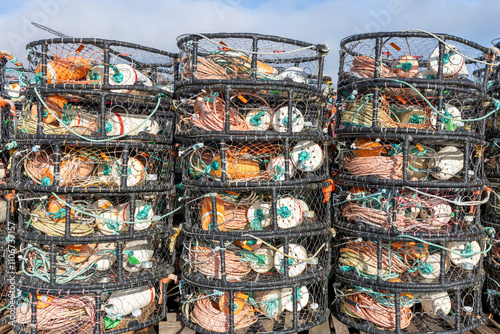 Detailed view of stacked crab pots, filled with ropes, buoys, and other fishing gear. 