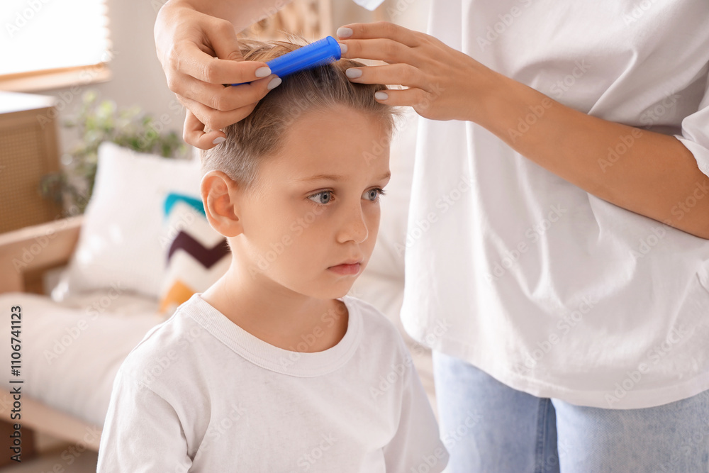 Mother brushing her little son's hair with pediculosis at home, closeup