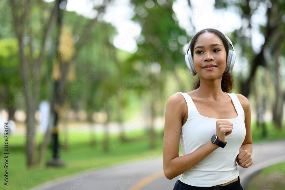 Young sporty woman on a morning jogging in the park, listening to music with headphones Young sporty woman on a morning jogging in the park, listening to music with headphones