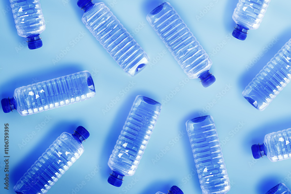 Pattern from Clear plastic water bottles with blue cap on light blue background with soft shadow, Minimal top view, themes of ecology, recycling, sustainable living, reduce disposable plastics Pattern from Clear plastic water bottles with blue cap on light blue background with soft shadow, Minimal top view, themes of ecology, recycling, sustainable living, reduce disposable plastics