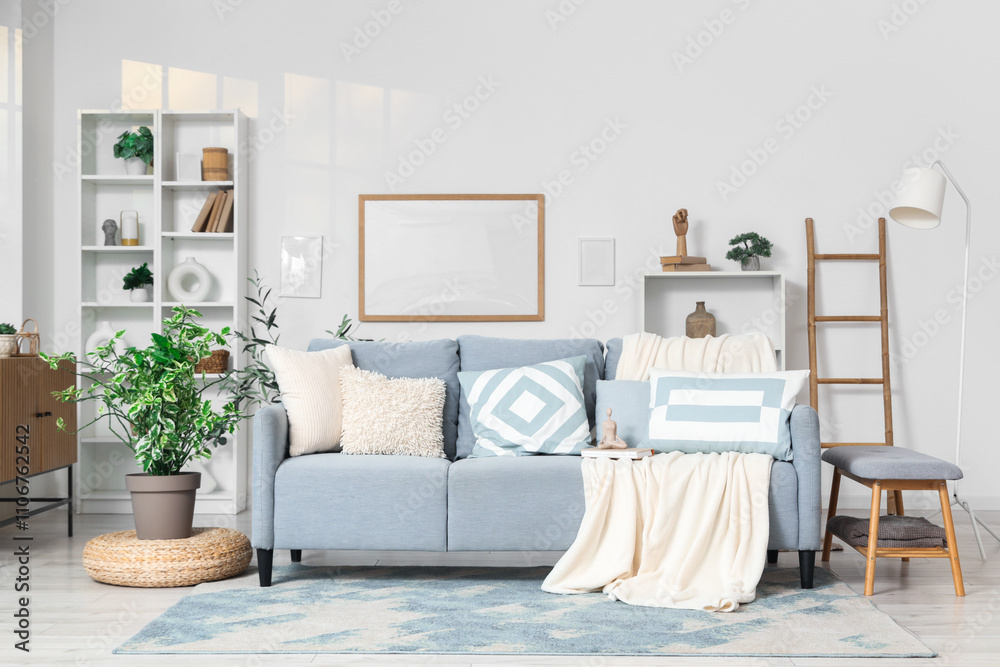 Fototapeta premium Interior of light living room with grey couch, shelf units and frames