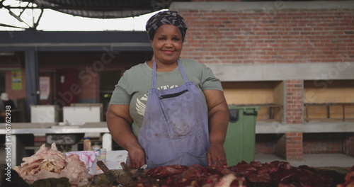 Portrait of a happy African female butcher wearing a headscarf in a township workshop, standing next