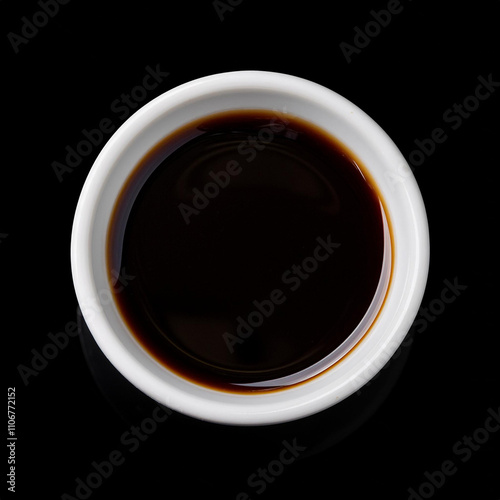 a small bowl of soy sauce isolated on black background photo