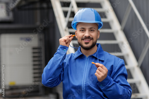 Male builder with earplugs outdoors photo