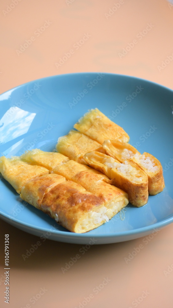 roll omelette stuffed with chesse and rice on blue plate, delicious food in the morning roll omelette stuffed with chesse and rice on blue plate, delicious food in the morning