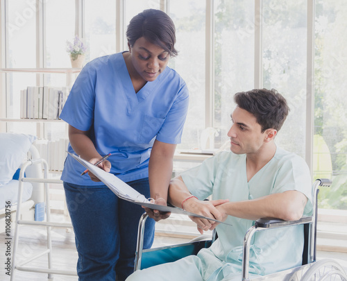 Business patient caucasian man sit wheelchair with woman nurse carer physical therapist black people two person look talk sign important document advice feel relax smile happy in hospital room service