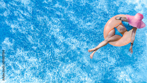 Beautiful woman in hat in swimming pool aerial drone view from above, young girl in bikini relaxes and swims on inflatable ring donut and has fun in water on tropical vacation on holiday resort