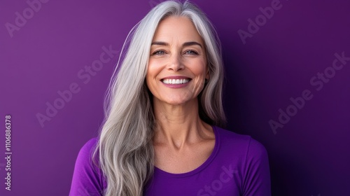 Cheerful beautiful mature woman with a vibrant smile standing against a purple background .Senior businesswoman, 60s grey haired lady professional female manager, leader looking at camera, copy space. photo