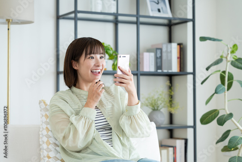 Plakat w ramie リビングでスマホを使う若い女性