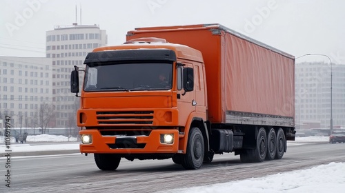 Orange Semi-Truck Driving on a Snowy Road in the City photo