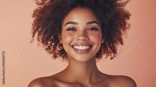 Happy African Beauty Model with Afro Hairstyle. Cheerful smiling Woman with Dark Skin and Black Coily Hair over Beige. Face and Body Care photo