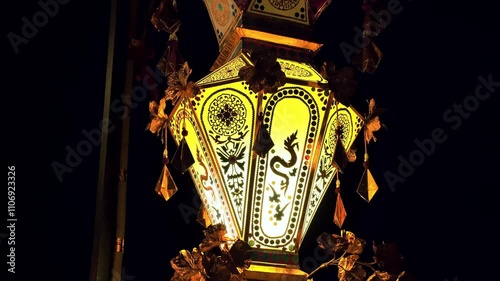 Traditional Thai lantern glowing warmly at night featuring detailed artistic patterns gold accents and dragon motifs, creating a festive ambiance outdoors for Loy Krathong festival Chiang Mai Thailand photo