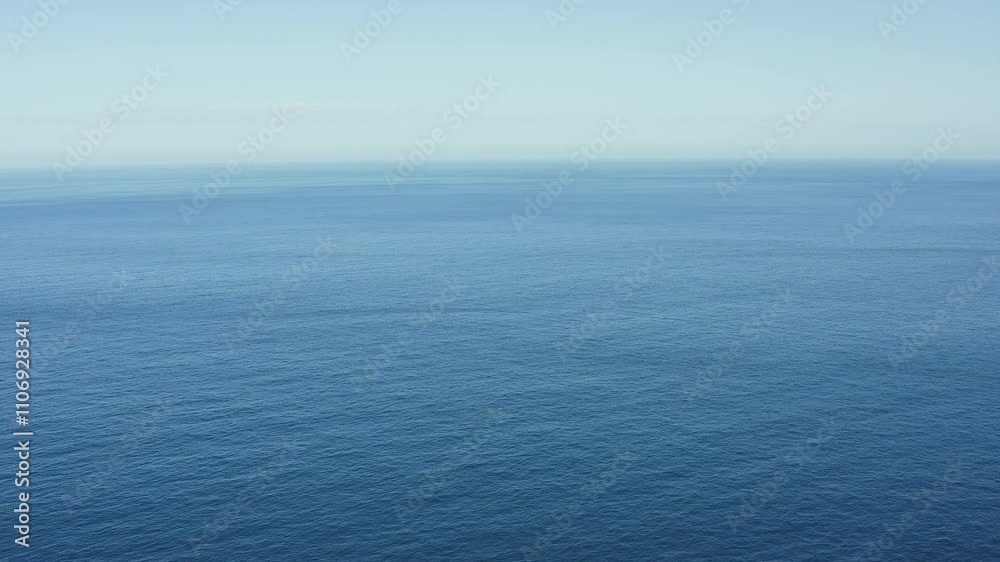 Side camera filming with a drone of the Cantabrian Sea on a calm morning, we see that everything is calm and the immensity is impressive with that blue color different from that of the sky Side camera filming with a drone of the Cantabrian Sea on a calm morning, we see that everything is calm and the immensity is impressive with that blue color different from that of the sky