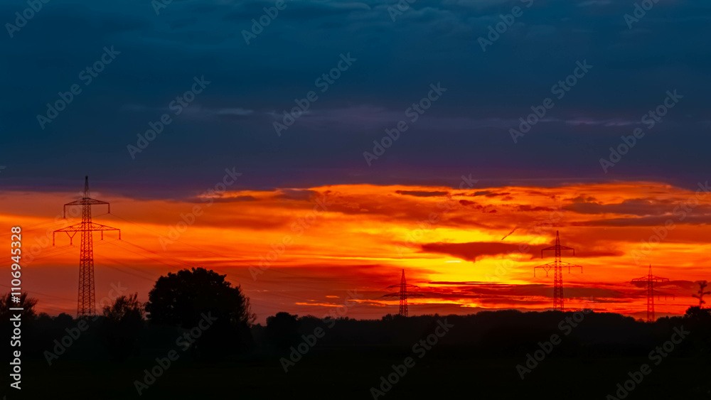 Summer sunset with a dramatic sky and overland high voltage lines near Tabertshausen, Deggendorf, Bavaria, Germany Summer sunset with a dramatic sky and overland high voltage lines near Tabertshausen, Deggendorf, Bavaria, Germany