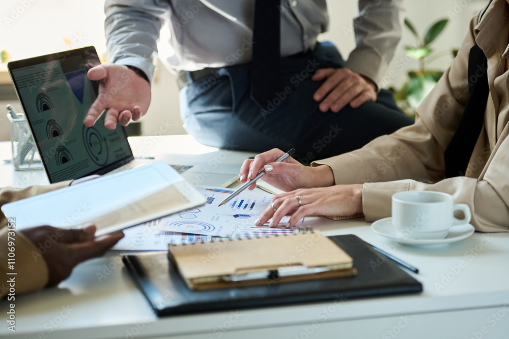 Focus on hands of young unrecognizable female broker pointing at paper document with financial graphic data during discussion Focus on hands of young unrecognizable female broker pointing at paper document with financial graphic data during discussion