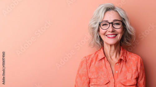 Obraz na płótnie Cheerful beautiful mature woman with a vibrant smile standing against a peach background w salonie