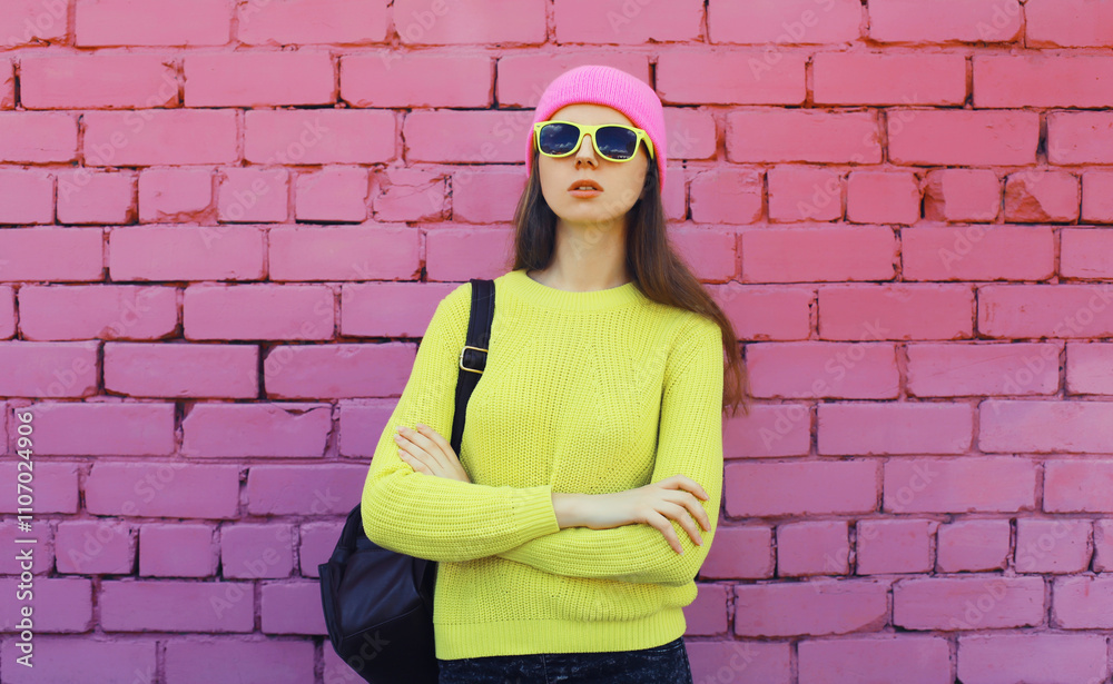 Stylish young teenager girl posing in vivid yellow colorful clothes on pink brick wall background