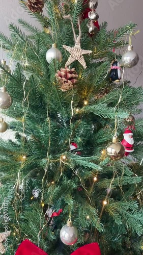 Close-up of a festive Christmas tree adorned with gold ornaments, pinecones, and string lights, creating a cozy holiday atmosphere.
