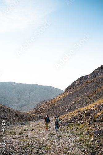 two girls on a walk in the mountains. girls with backpacks walk along a mountain path against the sky.