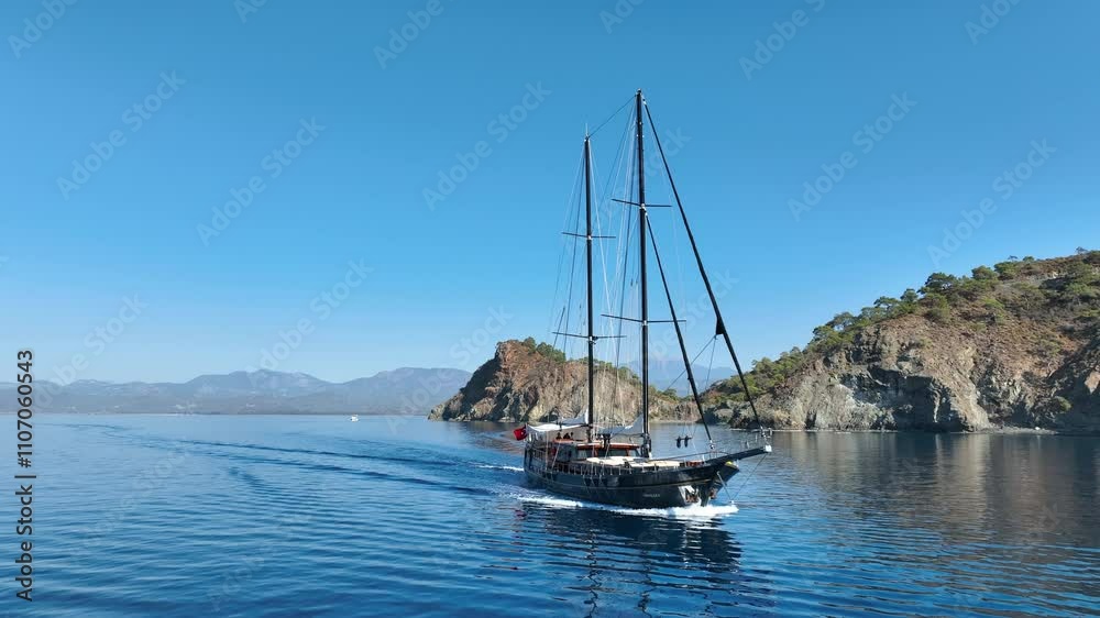 A gulet cruising smoothly on the open sea, with its sails catching the breeze and turquoise waters sparkling under the sun A gulet cruising smoothly on the open sea, with its sails catching the breeze and turquoise waters sparkling under the sun