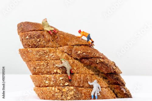 Miniature figurines climbing a stack of multigrain bread slices, resembling a rugged mountain. A whimsical and playful concept for food and adventure themes.