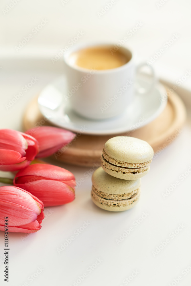 Close up of sweet french macarons, cup of tea or coffee and spring flowers on white background. Space for text. Close up of sweet french macarons, cup of tea or coffee and spring flowers on white background. Space for text.