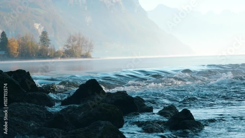 Crystal clear water gently flowing along Wessen lake’s edge with majestic Swiss alps in background. Serene, breathtaking scene of nature. photo