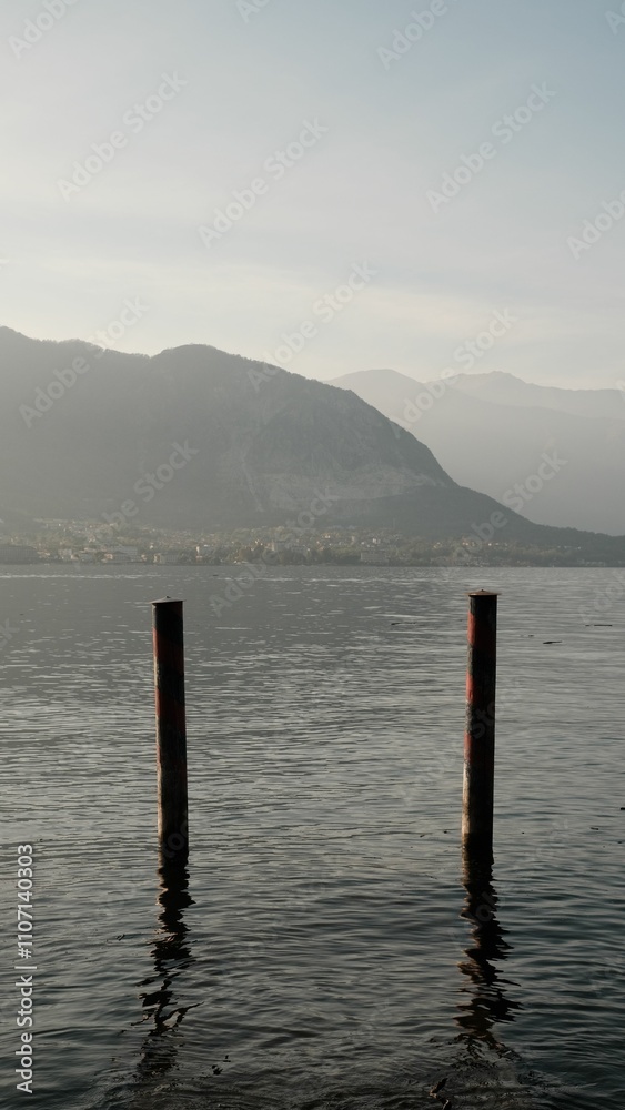 Serene lake view with mountains and wooden posts. Serene lake view with mountains and wooden posts.