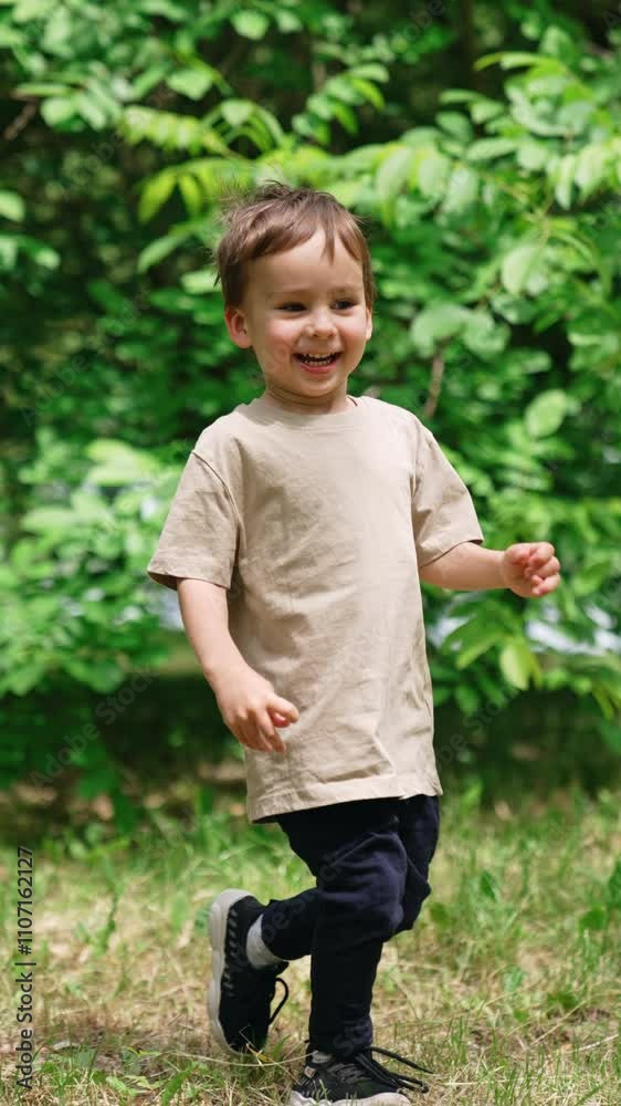 Cute happy Caucasian baby boy running joyfully in the park in summer. Time spending in the nature for a kid. Vertical video. Cute happy Caucasian baby boy running joyfully in the park in summer. Time spending in the nature for a kid. Vertical video.