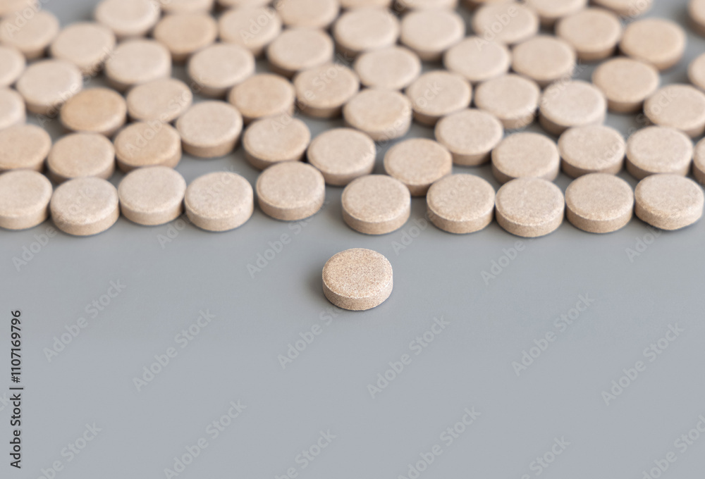 Pile beige herbal pills in a line on grey close up. Taking dietary supplements and vitamin Pile beige herbal pills in a line on grey close up. Taking dietary supplements and vitamin