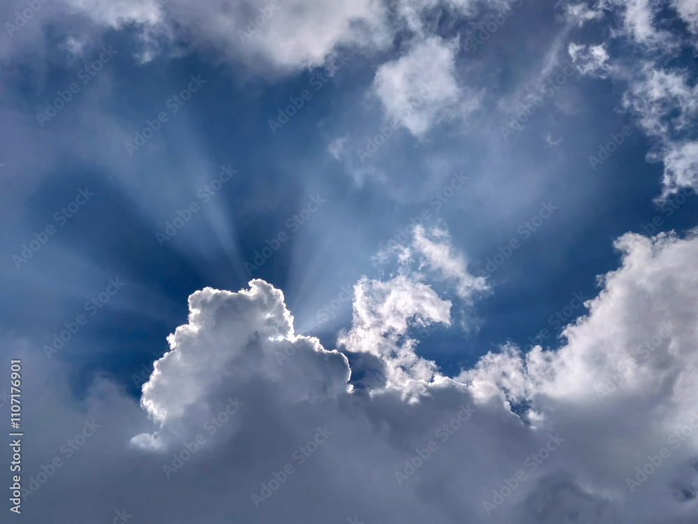 A beautiful blue sky with fluffy white clouds and radiant sunlight beams breaking through, creating a dramatic and serene atmosphere shot in India. Perfect for themes of hope, nature and inspiration. A beautiful blue sky with fluffy white clouds and radiant sunlight beams breaking through, creating a dramatic and serene atmosphere shot in India. Perfect for themes of hope, nature and inspiration.