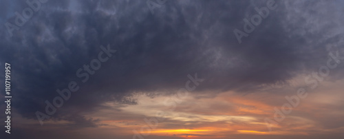 Panoramic cloudscape featuring a dramatic sunset with vibrant orange hues and contrasting dark clouds. , perfect for large backdrops and atmospheric displays.