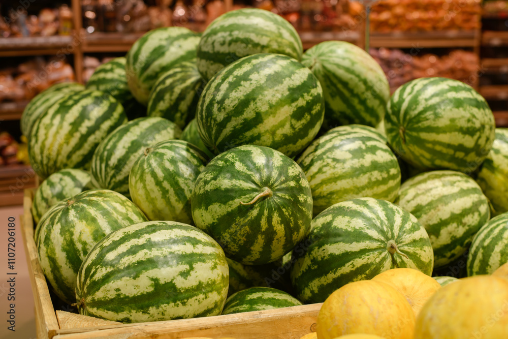 A large wooden crate filled with ripe watermelons. The watermelons are green and have dark green stripes. The crate is sitting on a shelf in a grocery store. A large wooden crate filled with ripe watermelons. The watermelons are green and have dark green stripes. The crate is sitting on a shelf in a grocery store.