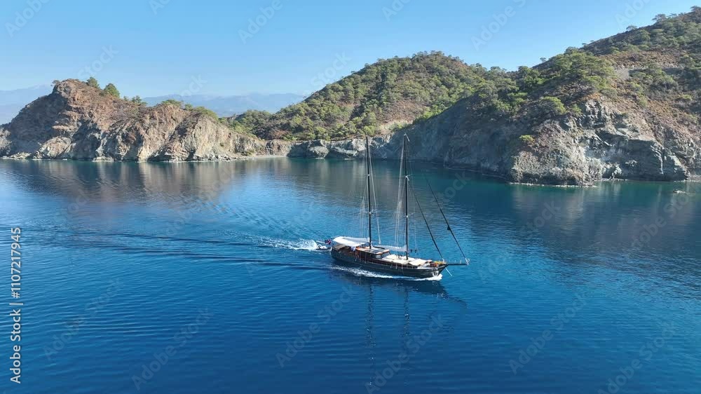 A gulet cruising smoothly on the open sea, with its sails catching the breeze and turquoise waters sparkling under the sun A gulet cruising smoothly on the open sea, with its sails catching the breeze and turquoise waters sparkling under the sun