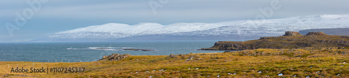 Landscape in panorama format with fjord and snow covered mountains in northwest Iceland