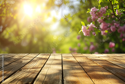 Fototapeta Naklejka Na Ścianę i Meble -  Sunlit wooden table with blossoming flowers and greenery in a spring garden