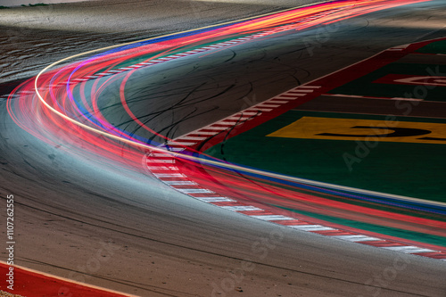 Long exposure night photography on the curve of the racing circuit, light trails of passing cars