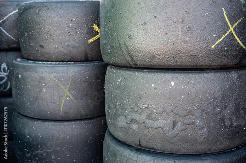 Detail of a stack of slick racing tires with pick up rubber, they have a discarded x